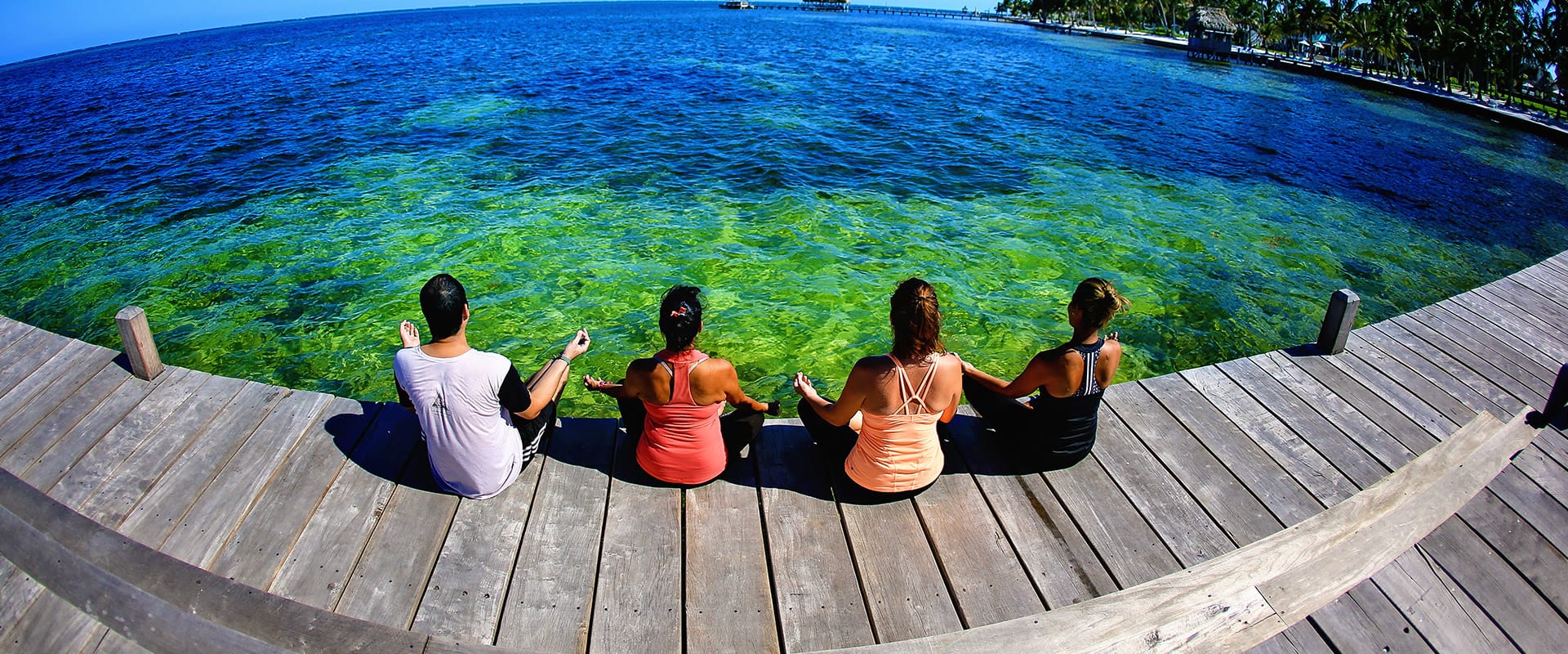 People sitting on the dock in Belize looking out over the Caribbean